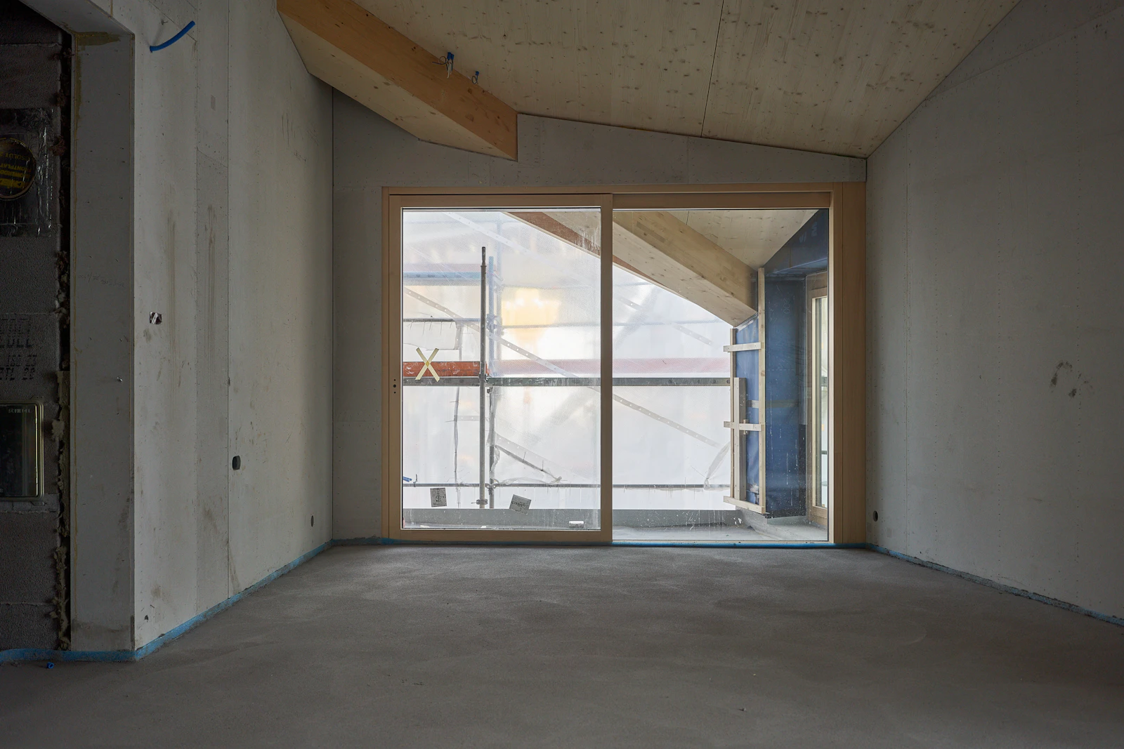 Rohbau einer Wohnung mit Betonwänden, Estrich und neu gesetztem Fensterelement
