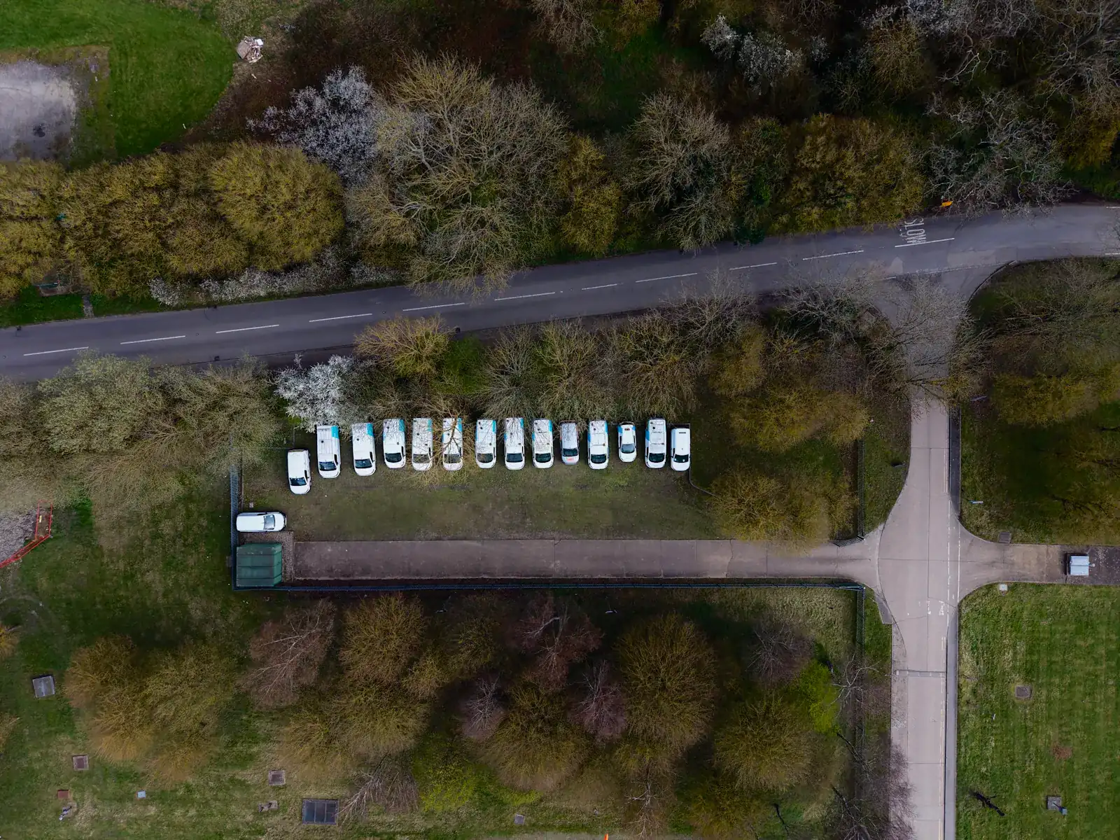 Luftaufnahme einer Reihe weißer Transporter auf einem Betriebshof