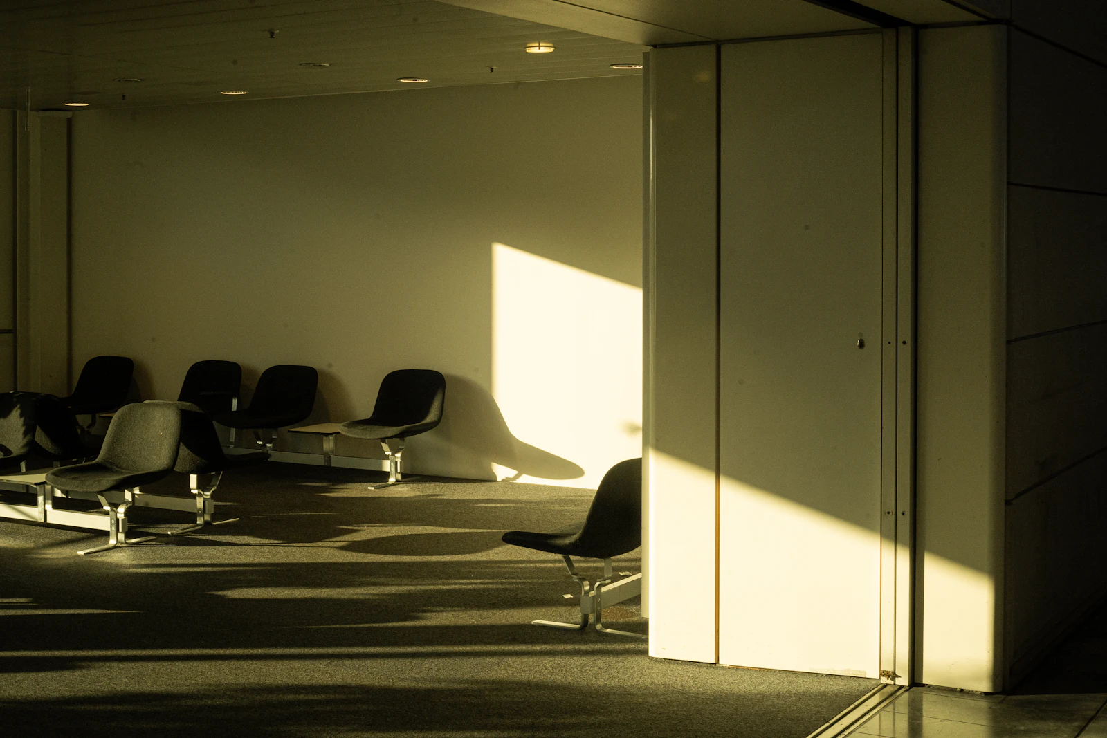 Leere Stuhlreihe in einem Wartebereich mit einfallendem Sonnenlicht
